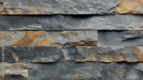 Close-up of a textured dark gray stone wall with layered natural slate stones stacked horizontally