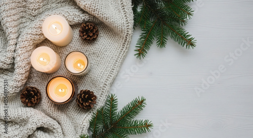 Cozy Winter Still Life with Candles Pinecones and Fir Branches on Soft White Blanket and Wooden Surface