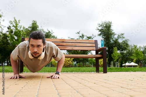 Sporty young man with beard engaged in outdoor workout routine in a park