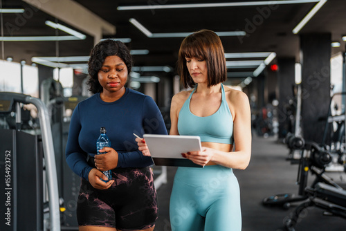 Canvas Print Personal trainer is guiding an overweight woman through a fitness plan on a tabl
