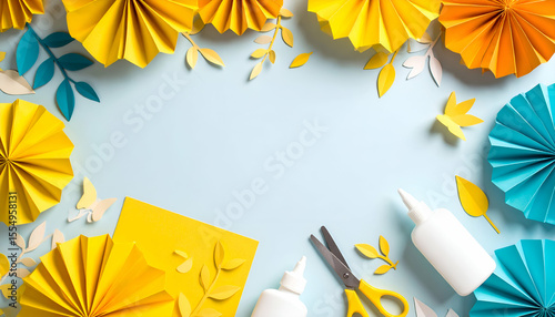 Colorful paper crafts and crafting supplies arranged on a light blue background.
