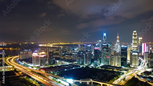 Vibrant Urban Skyline Night View Featuring Illuminated Skyscrapers and Modern Architecture with Light Trails on Highways and City Lights Over Large River in Dynamic Cityscape