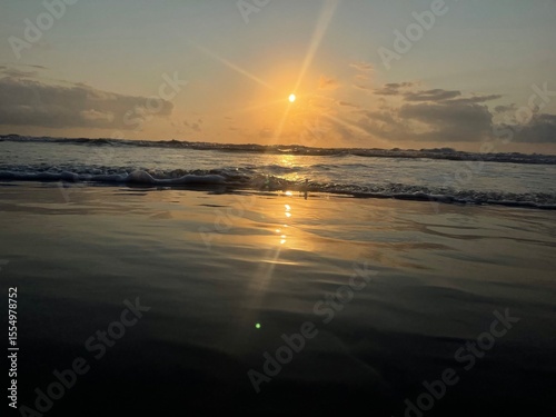 Sunrise at a tropical beach with soft golden tones reflecting on the calm sea. Peaceful and inspiring coastal view.