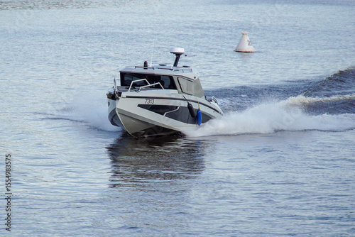 A speedboat glides across the water, creating waves, spray and foam.