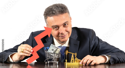 A middle-aged man in a business suit holds a red arrow of a financial growth chart in his hand, a gold oil pump and a $100 bill in a miniature shopping cart are on the table in front of him