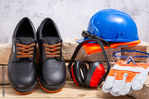 Personal protective safety equipment and old bricks on wooden background