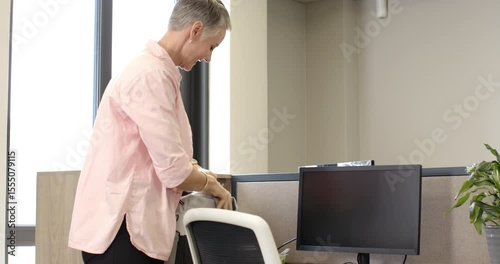Woman is entering workstation at arrival, adjusting chair, arranging documents to review with team