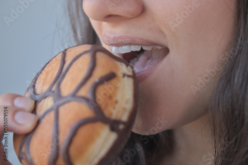 
Woman holding a chocolate donut in her hand. Industrial pastries, sweets, donuts