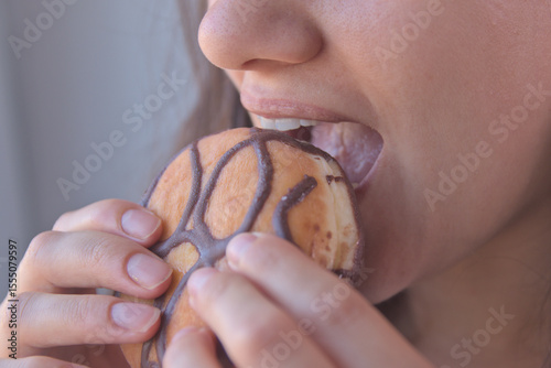 
Woman holding a chocolate donut in her hand. Industrial pastries, sweets, donuts