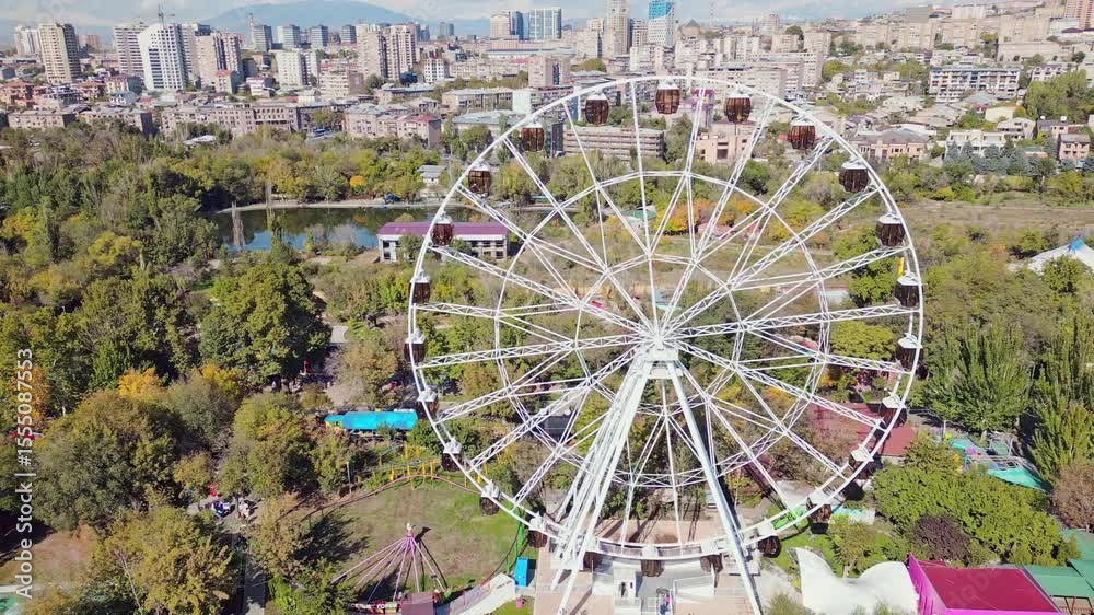 Yerevan, Armenia - 19th october, 2024: Aerial zoom out view ferris wheel in Victory Park ir with cityscape and buildings of Yerevan. Sunny autumn day carousels day out things to do concept