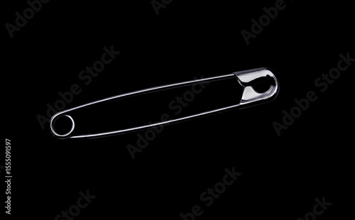 Freigestellte Sicherhitsnadel vor schwarzem Hintergrund