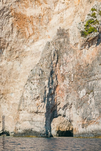 A stunning view of towering cliffs standing proudly above clear, calm waters. The sun reflects off the surface, creating a peaceful atmosphere perfect for exploration and admiration