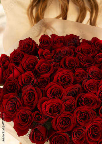 Bouquet of Red Roses Held by Woman in Soft Lighting for Romantic Occasion or Celebration
