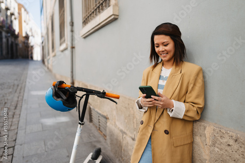 Asian woman using e scooter and app while exploring new city
