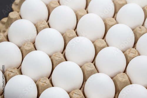 white chicken eggs in the cardboard egg tray with rooms for thirty eggs isolated on white background