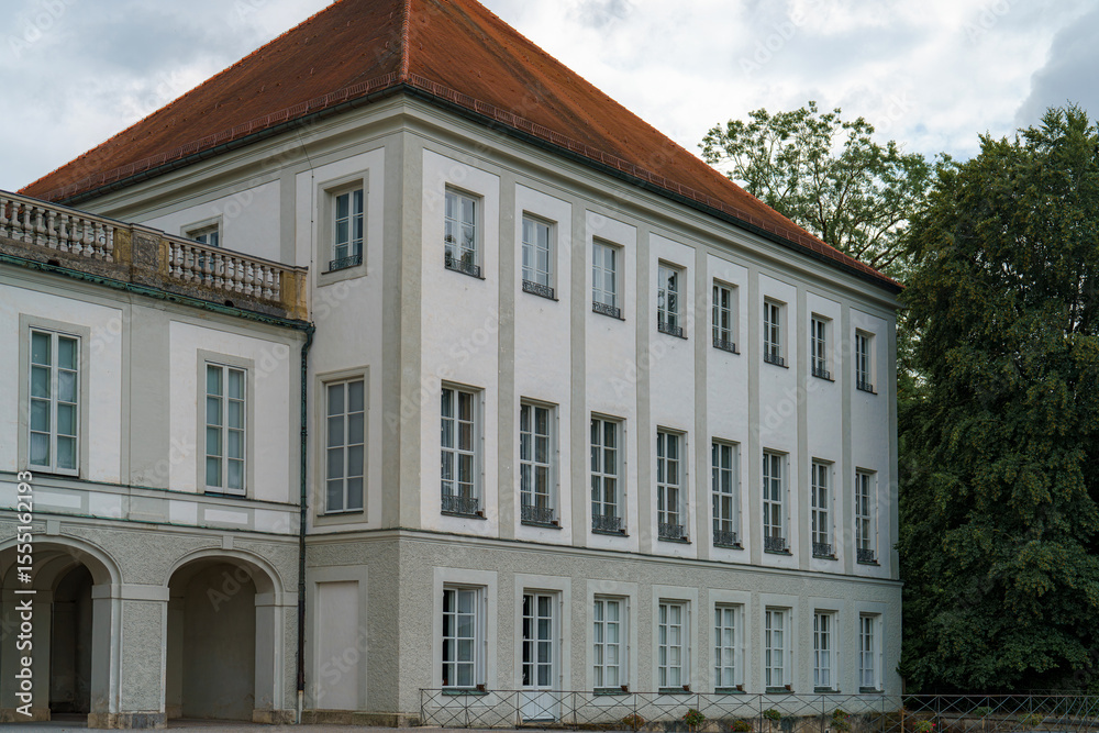 Fototapeta premium Historic building with white facade and red roof set against a cloudy sky at a serene location