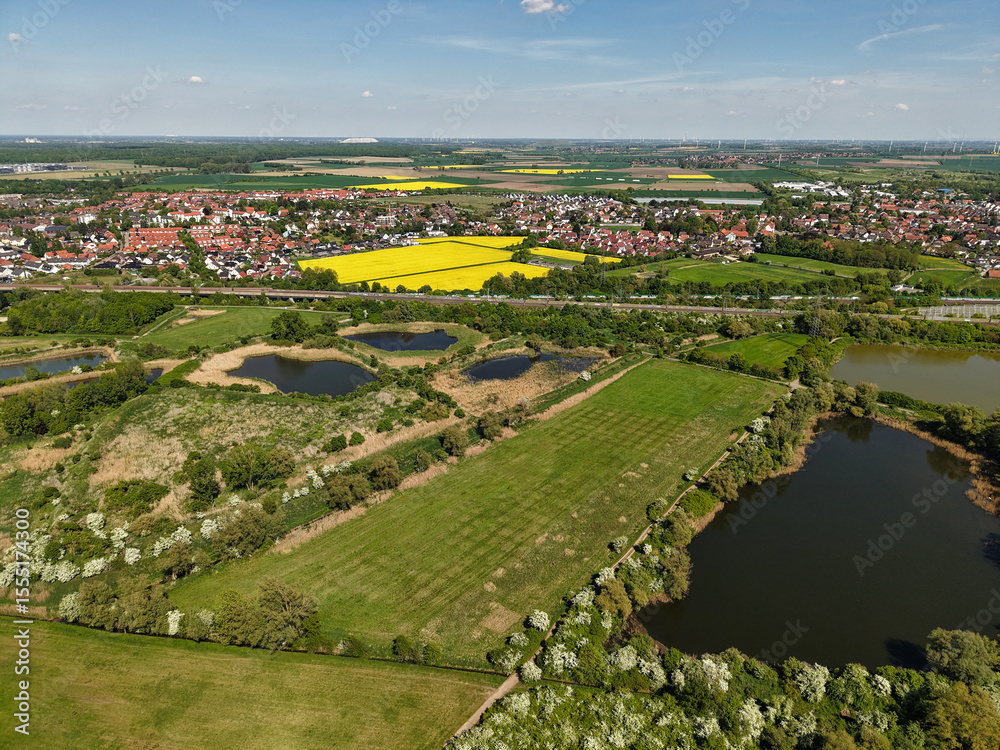 Fototapeta premium Stunning Aerial View of Colorful Vibrant Landscapes Featuring Fields and Water Bodies Koldinger Seen Hannover Pattensen