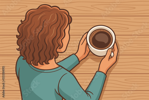 Top down view of a woman with curly brown hair holding a warm cup of coffee. Girl enjoying a hot beverage at a wooden table. Morning routine, coffee break and relaxation concept.