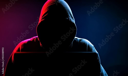 Hooded figure at a computer in dramatic lighting