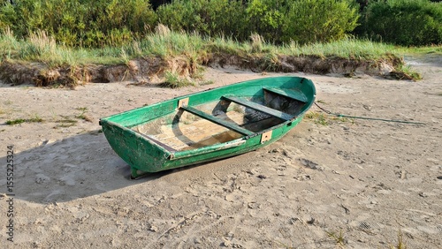 Small old green wooden pleasure boat on yellow sand in the Dunes in spring