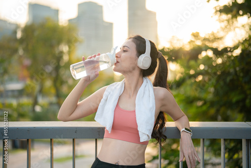 Woman hydrating after cardio with headphones
