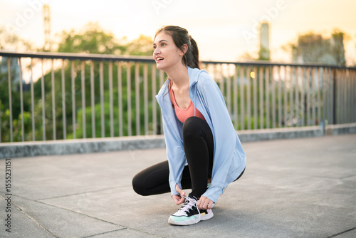 Asian woman tying shoelaces before outdoor workout
