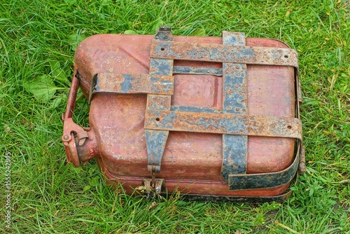 one closed lid retro brown with handle iron fuel industrial old motorcycle in case with plates canister lies on green grass day outside