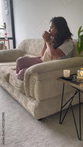Latina woman drinking tea in cozy living room with candlelight