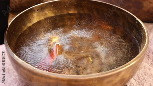 Water singing bowl starts vibrating, creating ripples and sound
