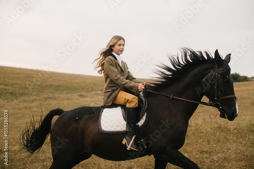 Young Woman Riding a Black Horse in a Scenic Open Field