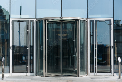 skyscraper in megalopolis with glass windows, central entrance with revolving door, business center in big city, multi-storey building, modern architecture, urban background