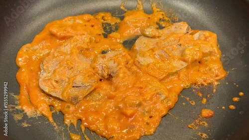 Sliced beef tongue simmering in a savory sauce in a pan