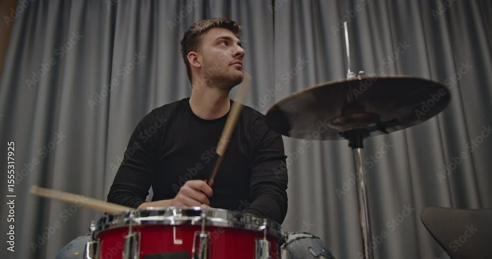 Drummer practicing in a rehearsal room before a concert. He is focused and passionate about his music. Drummer practicing in a rehearsal room before a concert. He is focused and passionate about his music.