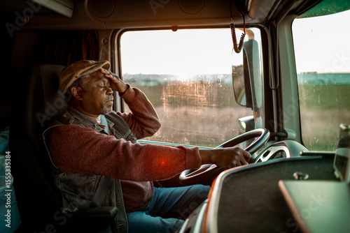 Wallpaper Mural Tired Black truck driver holding head while driving at sunset Torontodigital.ca