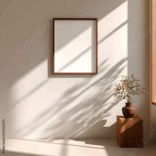 A wooden framed mockup poster hangs on a beige wall in a sunlit room