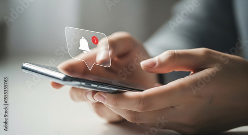 Woman using smartphone with new notification alert bubble. Digital bell icon showing unread messages or updates. Modern technology network.