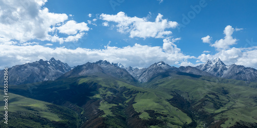 Aerial view of beautiful high altitude snow capped mountains and forest grassland landscape in China