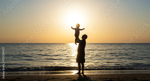 Silhouette of a person holding up a child on a beach with a bright sun in the background