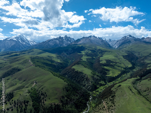 Aerial view of beautiful high altitude snow capped mountains and forest grassland landscape in China