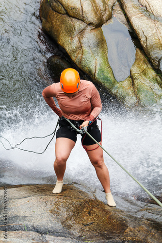 Female canyoneer skillfully descending a waterfall, showcasing courage and athleticism in the thrilling world of extreme sports