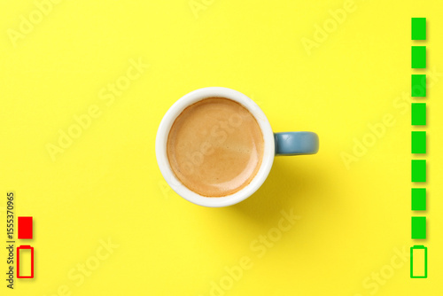 Cup of coffee, low level and fully charged battery indicators on yellow background, top view. Restoring energy with caffeine