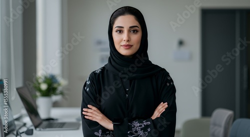 Confident Emirati businesswoman in traditional abaya, arms crossed, exudes strength and elegance.