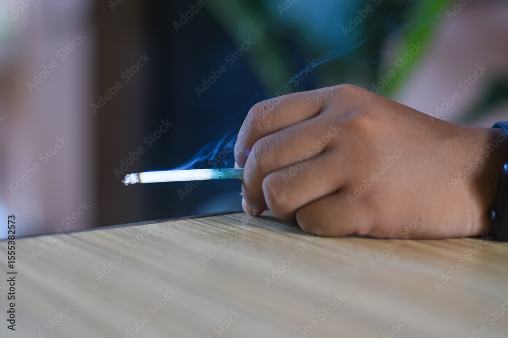Obraz premium man holding a cigarette. Cigarette smoke spread. 