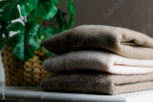 Three pieces of cashmere sweaters on a white closet with a flower.