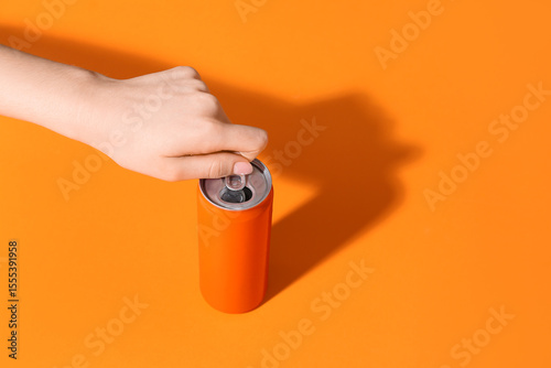 Female hand opening soda can on orange background