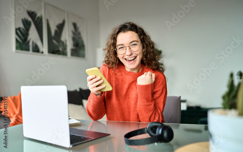 Portrait of happy woman student feeling excited winner holding cellphone using mobile phone winning online, receiving great news or sms offer on smartphone, getting new job celebrating success.