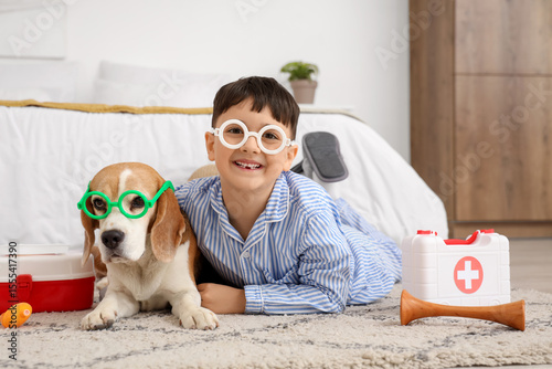 Funny little doctor with Beagle dog in eyeglasses lying on floor at home