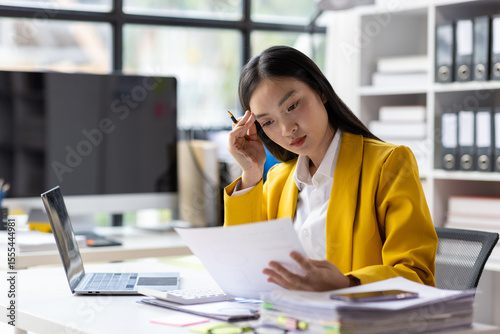Serious female accountant working with financial documents in office and auditing accounts. Auditor checking financial report documents on desk.