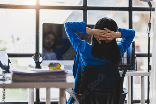 Businesswoman working on computer at office. She was stretching to relieve herself from sitting in an office chair for a long time.