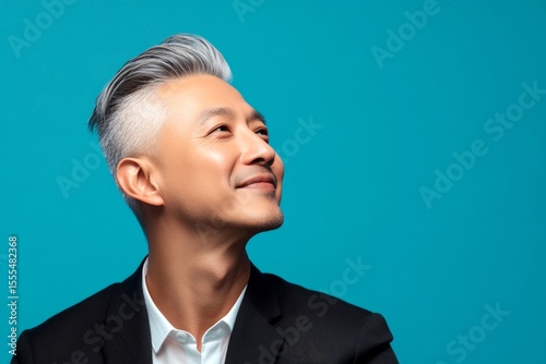 Idea of style for aging men. A charismatic and fashionable male with a trendy look. Blue solid background. Elegant men's soft perm haircut - midlife asian man with short hair.